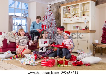 Two Generation Family opening presents at christmas time. They are looking at each other and wearing christmas clothing.