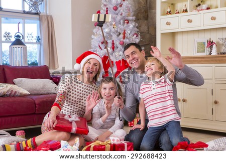 Two Generation Family taking a Self Portrait at Christmas. They are using a Selfie Stick and waving at the Camera.