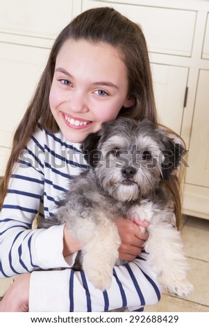 Young girl holding a Puppy. She is looking at the Camera and smiling.