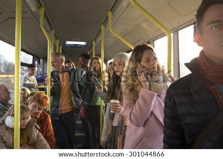 Different people can be seen traveling on the bus. Some are talking to other people, others are using technology or looking out the window.