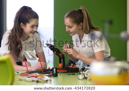 Two female students are working together in school to build a functioning robotic arm.