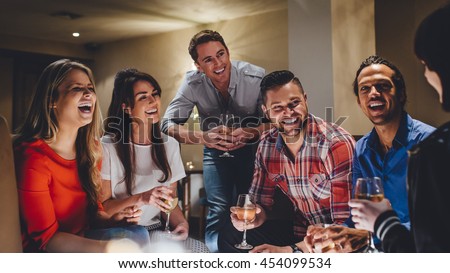 Large group of friends enjoying a glass of wine together in a bar.
