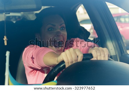 Brunette young woman sitting behind the wheel of the car and yells