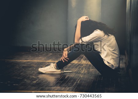 Lonely sad woman cry and hug her knees sitting in the dark corner ,Sad woman Unhappy and stressed student on the campus ,Family problems and education concept