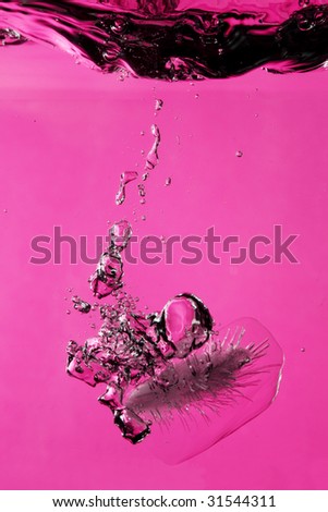 Ice splashing on water against pink background