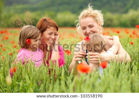 Two women with children in poppy field
