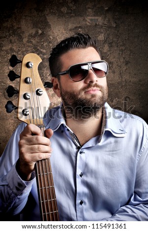 Bass player with glasses posing against grungy background