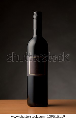 Black wine bottle with empty label isolated against dark background