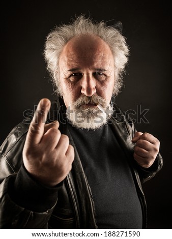 Grumpy man with cigarette against black background