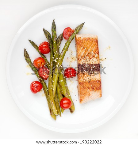 Salmon fillet with asparagus and cherry tomatoes on white plate