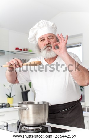 Elderly chef in kitchen preparing food