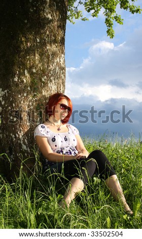 Absent minded woman leaning on the tree trunk