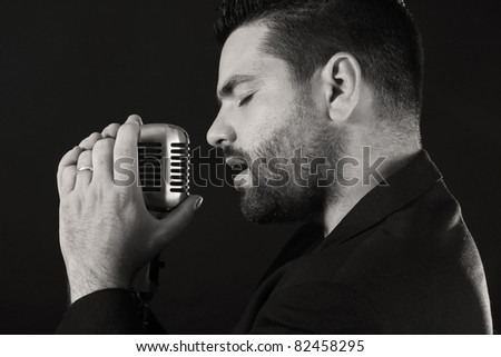 Portrait of male  singer  with old fashioned microphone against black background
