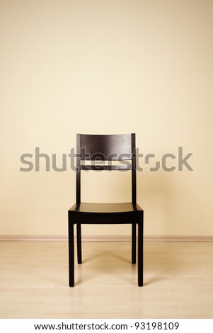 One chair in front of yellow wall