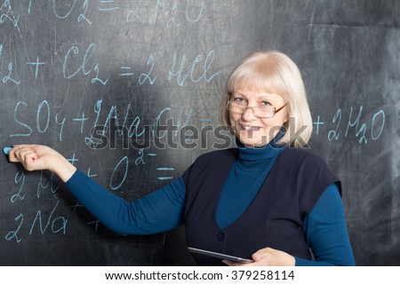 Mature women teacher showing formulas on the blackboard