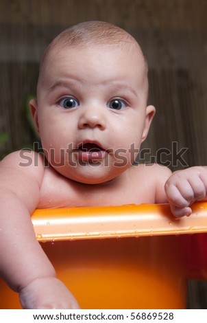 Small cute surprised child in orange bath