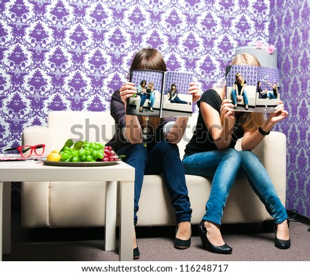 Two Girlfriends On A Sofa Read The Magazine