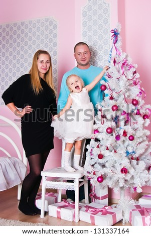 The girl with parents at the Christmas fir-tree with gifts