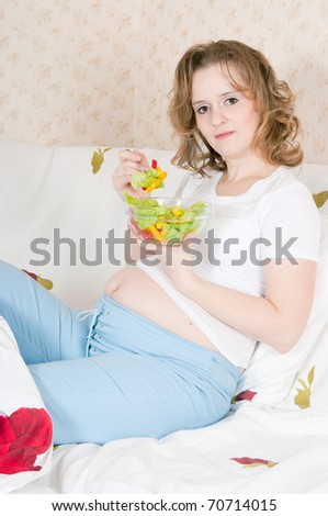 The image of Pregnant woman in bed eating salad