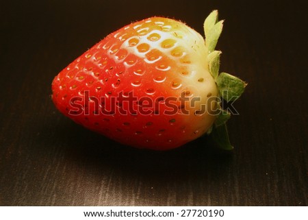 Side view of a straw berry on a dark back ground…