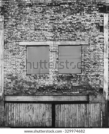 Industrial white heavily damaged factory brick wall with windows.
