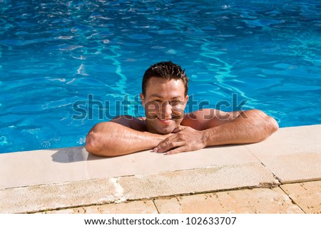 wet tanned young man posing in the swimming pool