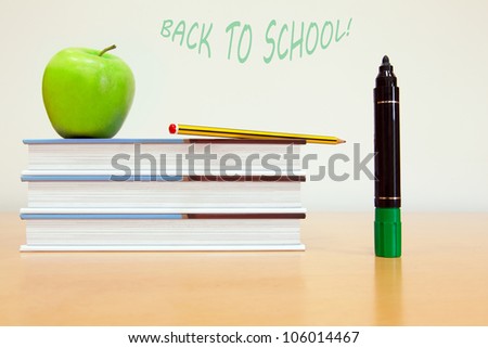School books with apple on desk at modern classroom