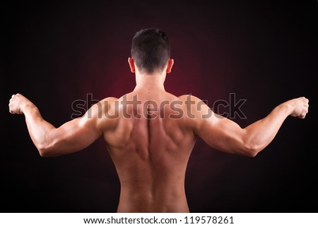 Muscular young man from back on black background