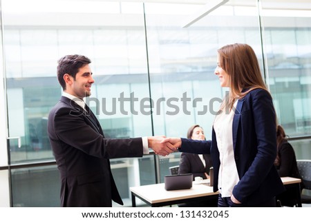Business handshake at modern office with bussiness people on background