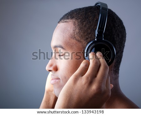 Afro man listening to music on DJ headphones with eyes closed
