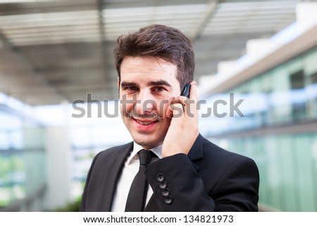 Closeup portrait of smiling young business man using cell phone at the office