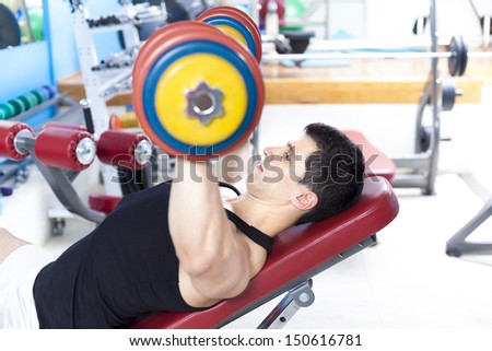 Strong man lifting heavy free weights at the gym