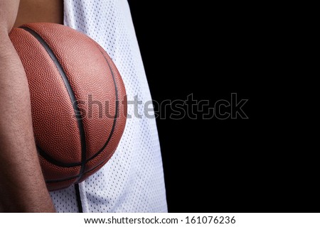 Basketball player holding a ball against dark background