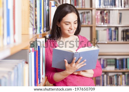 Portrait of a smiling young student reading a book in a library