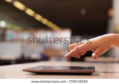 Hand pointing to tablet computer in library