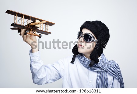 Happy kid playing with toy airplane against gray background