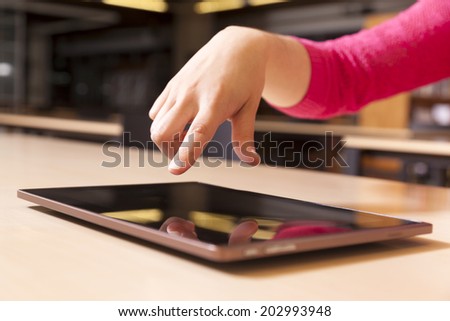 Hand pointing to tablet computer in library