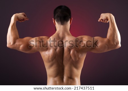 Young bodybuilder showing his back muscles on a dark background