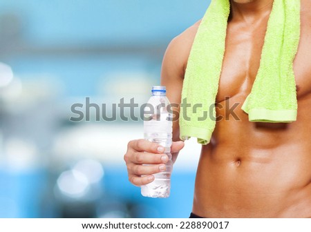 Fitness man holding a bottle of water at the gym
