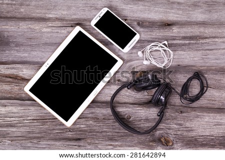 Digital tablet and smart phone with headphones and earphones on wooden background