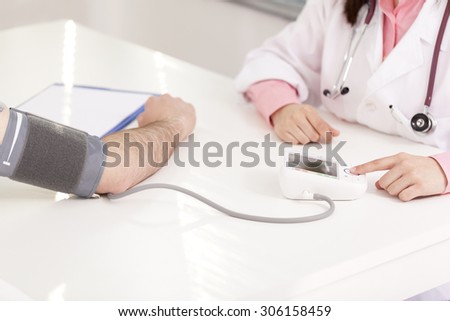 Top view of female doctor checking man blood pressure at the clinic