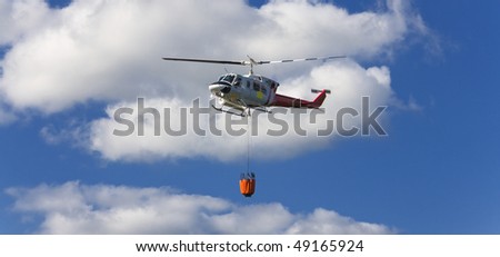Fire fighting helicopter with waterbag on his way to combat the forest fire