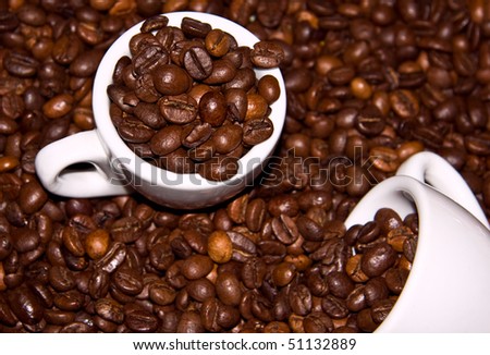 Close up of white coffee cup on brown roasted beans as background.