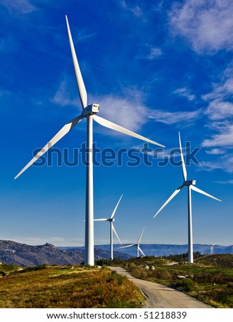 windmills in the top of a montain with blue sky and clouds, alternative energy source