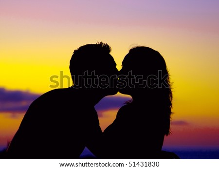 Silhouette of couple kissing at sunset