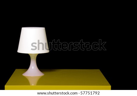 White modern lamp on a yellow table against dark background