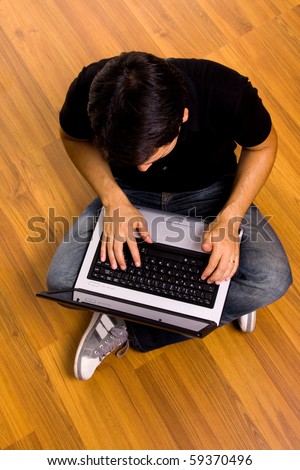 young man sitting on the floor working on laptop computer at home