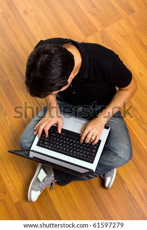 young man sitting on the floor working on laptop computer at home. Focus on the head