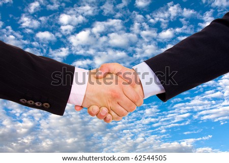 Business men hand shake over a blue sky with clouds as background
