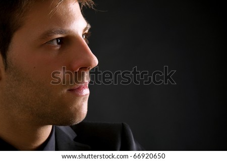 Profile picture of young man\'s portrait. Close-up face against black background